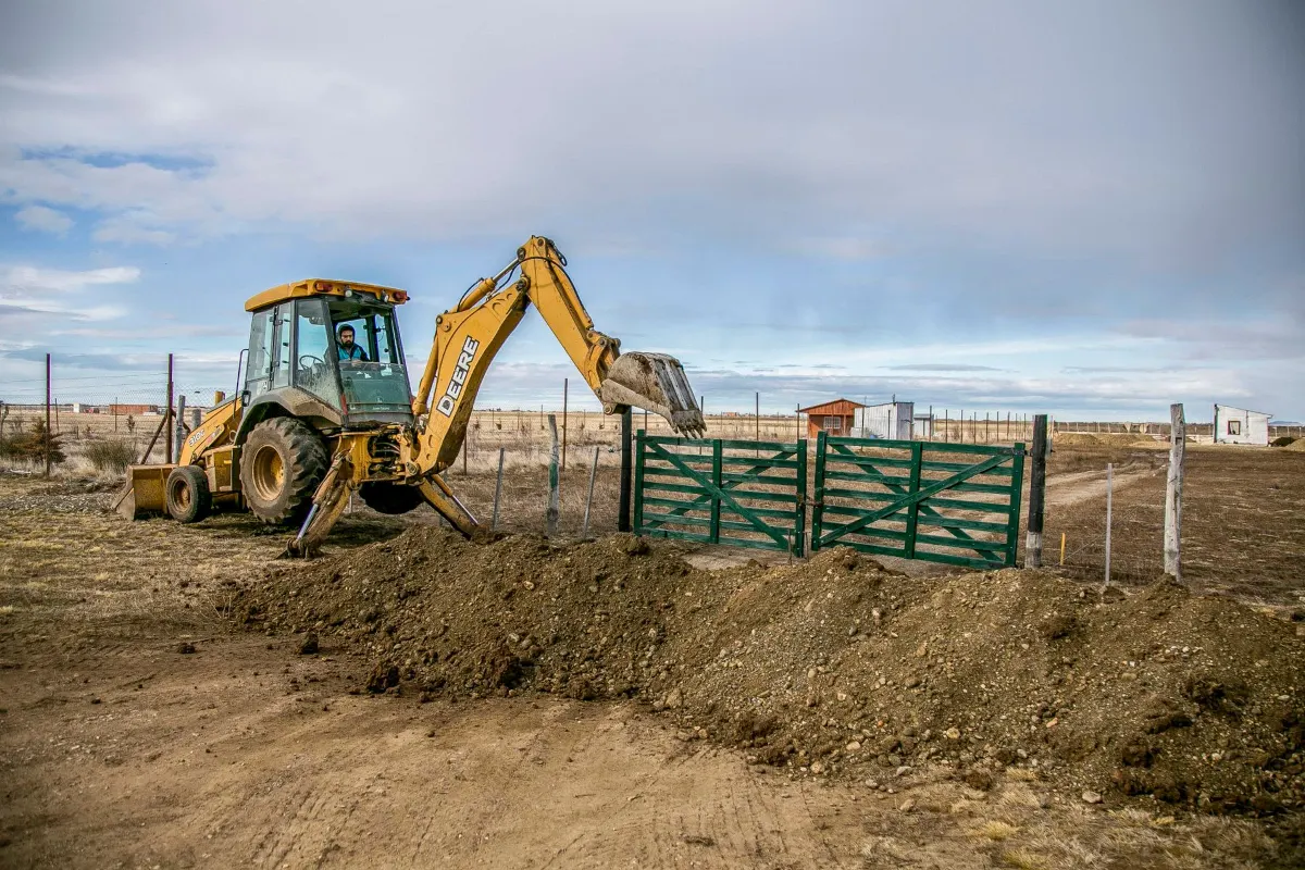 Backhoe working inside a fenced yard