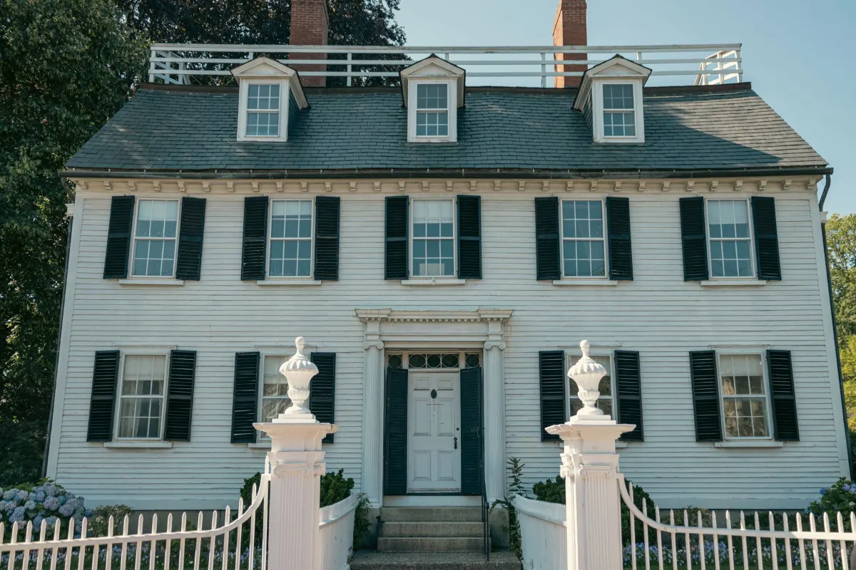 Colonial house behind a white fence